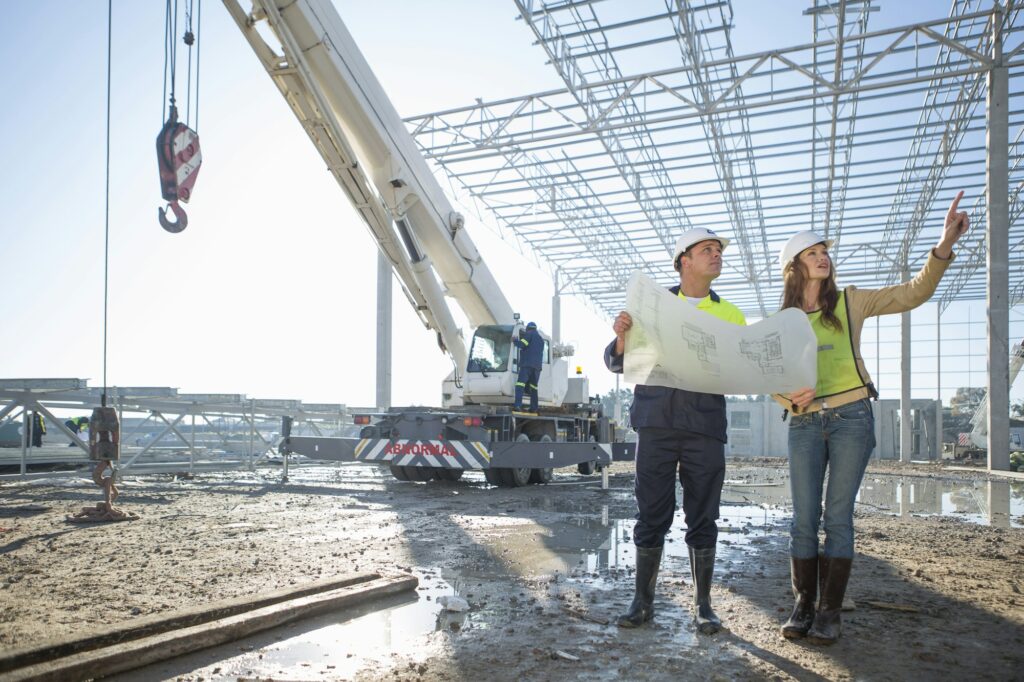 Site manager and architect checking blueprint on construction site